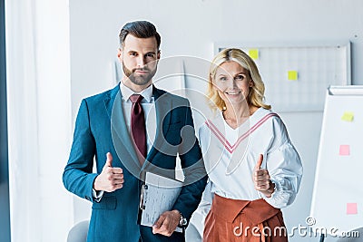 Recruiter and blonde woman showing thumbs up in office Stock Photo