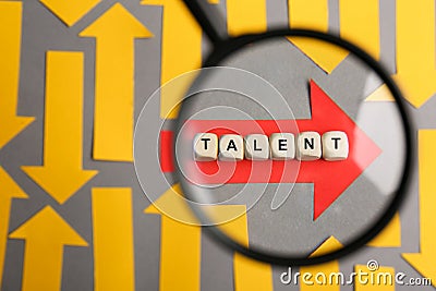 Recruitment process, searching for employee. View through magnifying glass of red paper arrow and word Talent made of wooden cubes Stock Photo