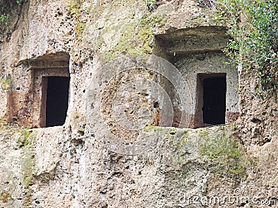 The rectangular entrances to Etruscan tombs carved in the wall of a tufo cliff Stock Photo