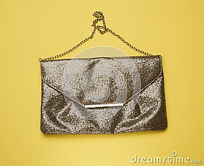 Rectangular golden leather fashion clutch on a metal chain on a yellow background Stock Photo