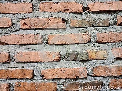 Rectangular patterned orange brick wall with rough-textured gray cement Stock Photo