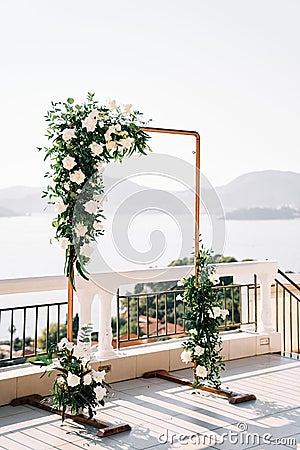 Rectangular wedding arch stands on a terrace above the sea against the backdrop of mountains Stock Photo