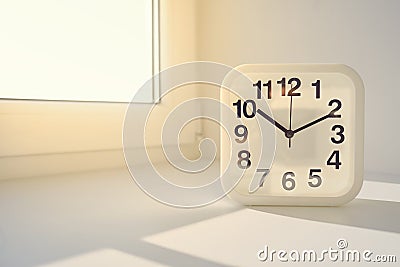 Rectangular white alarm clock on sunny window background. Stock Photo