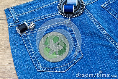 Recycle clothes icon patch on jeans, sustainable fashion visible mending concept Stock Photo