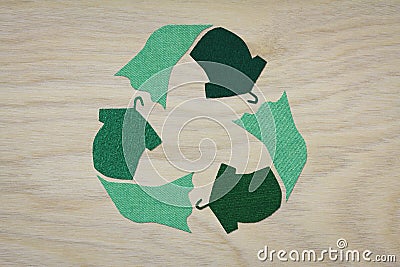 Recycle clothes symbol recycle sign cut from reuse textiles on a wooden background, sustainable fashion concept Stock Photo