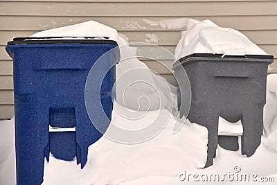 Garbase and recycling cans sit outside in the snow Stock Photo