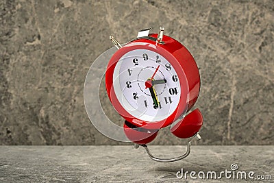 Red alarm clock falling on the stone background Stock Photo