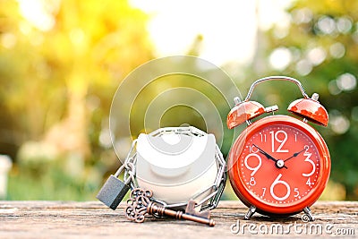 Red alarm clock with piggy bank a key on old wood Stock Photo