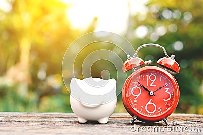 Red alarm clock with piggy bank on old wood Stock Photo