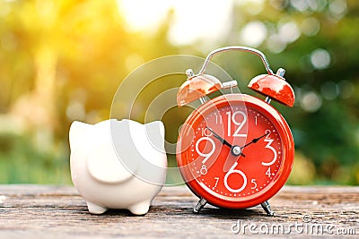 Red alarm clock with piggy bank on old wood Stock Photo