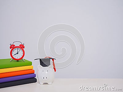 Red alarm on stack hardcover book, Piggy bank with graduation hat, Copy space for text, Back to school, Education concept Stock Photo