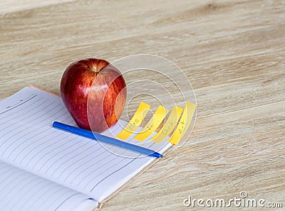 Red apple, blue pen And a white note book with a wooden background,selective Focus Stock Photo