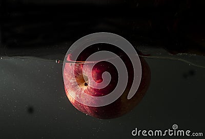 Red apple floating inside the water with dark background Stock Photo