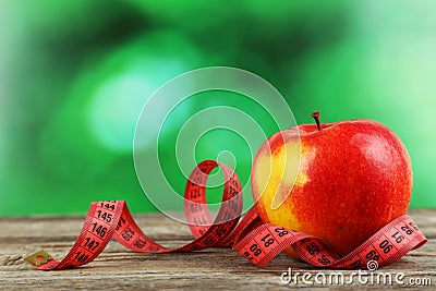 Red apple with measuring tape on grey wooden background. Stock Photo