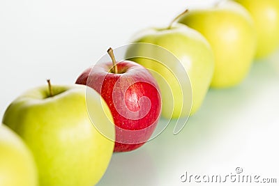 Red apple standing out from row of green apples. Stock Photo