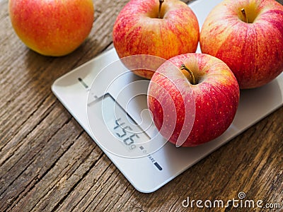 Red apples on kitchen scale on wooden background. Product weighing Stock Photo