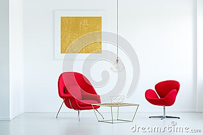 Red armchairs at gold table in minimal white flat interior with Stock Photo