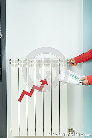 Red arrow of price increase on heating radiator. Woman with bill closes heating. Vertical photo Stock Photo