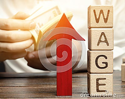 Red arrow up near wooden blocks with the word Wage and a businessman. Salary increase concept. Wages rate. Revenue growth and Stock Photo