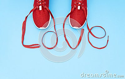 Red athletic shoes and lettering love made of the shoelaces on a blue background Stock Photo