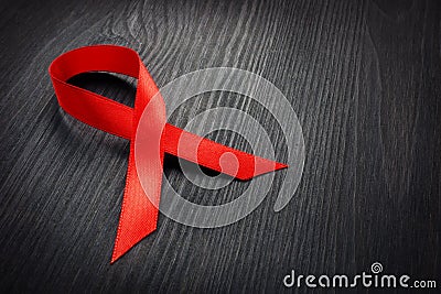 Red awareness ribbon on a dark desk. HIV AIDS Stock Photo