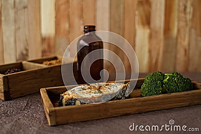 The red baked fish with broccoli, in a wooden posyda, a useful lunch, a dinner, a diet, food. Stock Photo