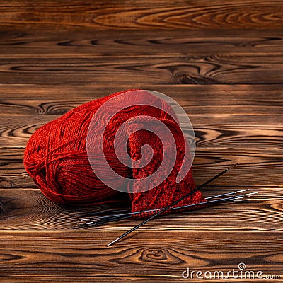 Red ball of yarn and knitting needles with knitting on wooden background Stock Photo