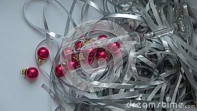 A dynamic composition for a festive mood, consisting of bright red Christmas balls and a transparent sparkling wine glass Stock Photo