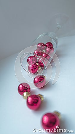 A dynamic composition for a festive mood, consisting of bright red Christmas balls and a transparent sparkling wine glass Stock Photo