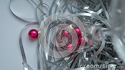 A dynamic composition for a festive mood, consisting of bright red Christmas balls and a transparent sparkling wine glass Stock Photo