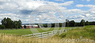 Red barns, wood fence, green pasture, blue sky Stock Photo