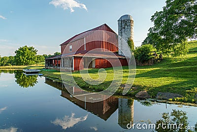 Red barn and grain silo reflected in a pond on a summer day Stock Photo