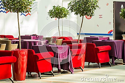 Red and beige armchairs are next to the restaurant tables, which are covered with long burgundy tablecloths Stock Photo