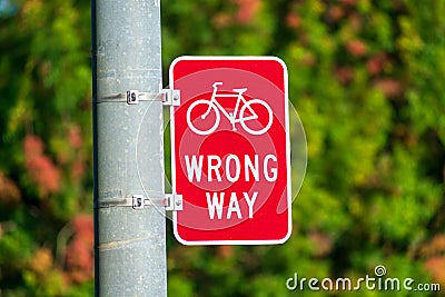 Red bicycle wrong way sign on street pole placed facing wrong-way bicycle traffic Stock Photo