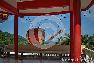 Red big drum with stick hanging on the top of a hill in a gold buddhist temple Stock Photo