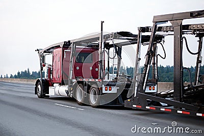 Red big rig classic semi truck car hauler with empty trailer run Stock Photo