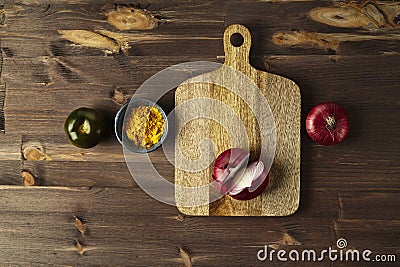 Red bisect onion, tomato, yellow spice on wooden table with cutting board. Stock Photo