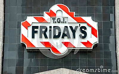 Red and Black T.G.I Friday`s sign logo on a wall above a restaurant Editorial Stock Photo