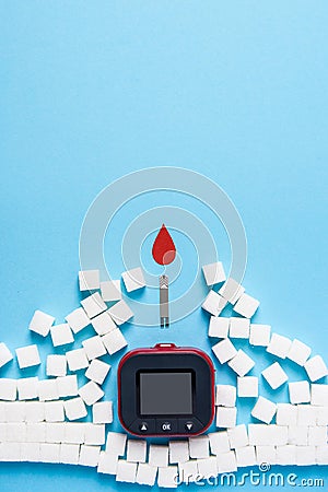 Red blood drop and wall made of sugar cubes ruined by Blood glucose test strips and Glucose meter on blue background Stock Photo