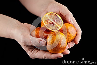Red or blood orange fruits in hands on black background Stock Photo