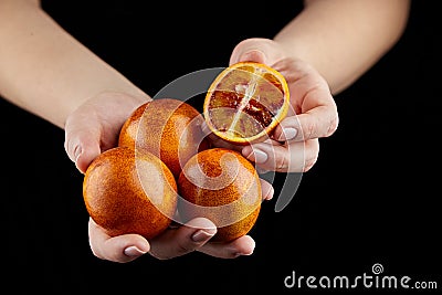 Person holging handful of half and whole red or blood oranges on black background Stock Photo