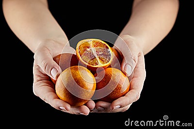 Person holging handful of half and whole red or blood oranges on black background Stock Photo