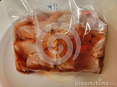 red bloody meat thawing in a plastic bag in water Stock Photo