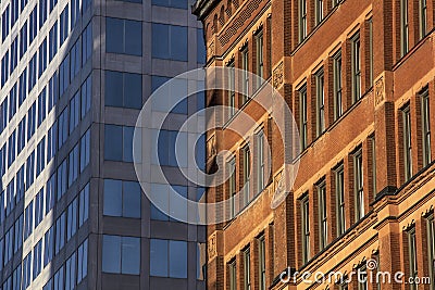 Red brick older architectural brick office building in front of modern glass business office building Stock Photo