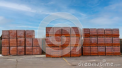 Red brick packed in stacks are stored on ground outdoors at a hardware store warehouse. Building bricks on pallets on an outdoor. Stock Photo