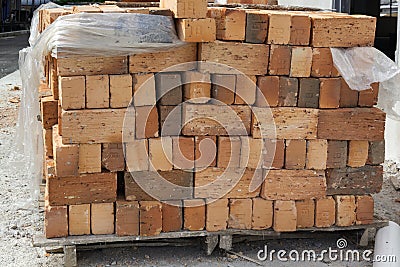 Red brick stowed on a wooden flight at a construction site. Stock Photo