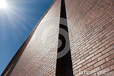 Red brick wall facade against blue sky and sun beams. Stock Photo