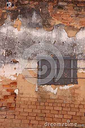 Red brick and white plaster exterior wall with barred and boarded window Stock Photo
