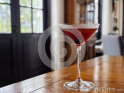 Red-brown cocktail with an olive in a martini glass during daytime with copy space Stock Photo