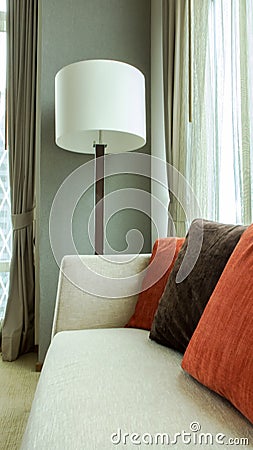 Red and Brown Decorative Pillows on a Casual Fabric Sofa with Big White Lamp in the Living Room Stock Photo